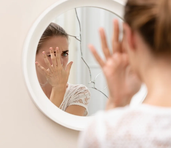 Девушка смотрит в разбитое зеркало